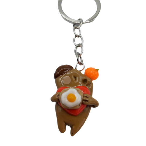 Llavero de capybara sosteniendo un huevo frito y un corazón rojo, hecho a mano.